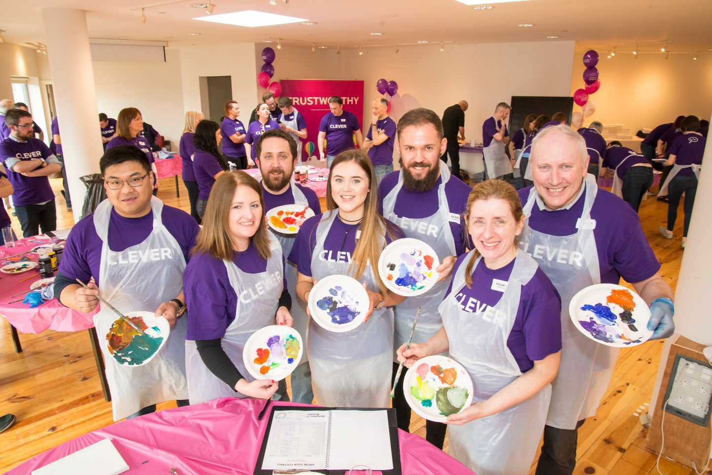 Corporate team smiling while holding painted plates during a collaborative team building activity called The Big Picture in Ireland
