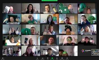 A vibrant virtual St. Patrick’s Day event featuring a multinational corporate team on a video call. Participants are dressed in festive green attire, holding Irish-themed props, and giving thumbs-up, creating an engaging and celebratory atmosphere. The Dynamic Events logo is visible, reinforcing the corporate virtual team-building theme.