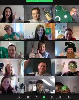 A vibrant virtual St. Patrick’s Day event featuring a multinational corporate team on a video call. Participants are dressed in festive green attire, holding Irish-themed props, and giving thumbs-up, creating an engaging and celebratory atmosphere. The Dynamic Events logo is visible, reinforcing the corporate virtual team-building theme.