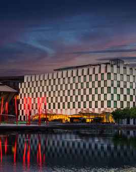 The exterior of the Anantara Hotel looking over River Liffey at night time with big red LED lights outside and the hotel is lit up for corporate events
