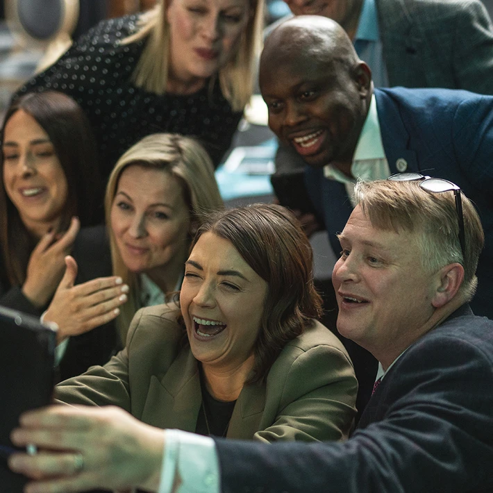 Corporate team laughing and taking a group selfie during a high energy indoor team building activity in Ireland