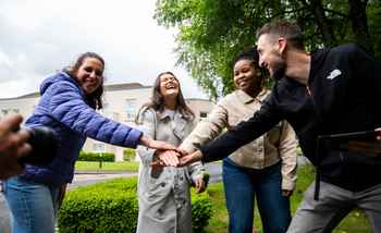 Corporate team building activity in Ireland with colleagues smiling and joining hands outdoors during an August team event.