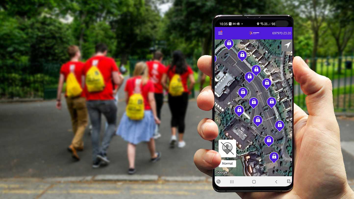 Corporate team building activity outdoors with employees walking to locations and solving app-based digital treasure hunt challenges on a mobile device