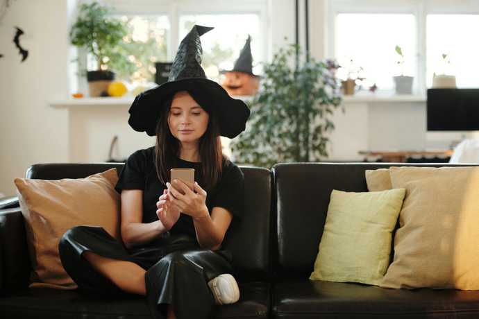 A witch sitting in her sitting room with a phone