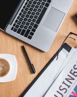 top view of business workplace with laptop and newspaper