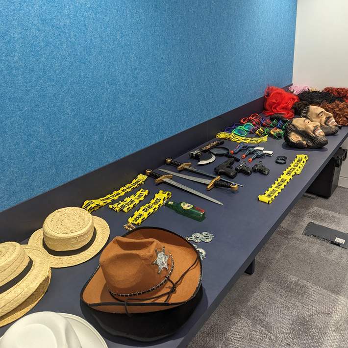  A table packed with props, disguises, and crime-solving tools, from detective hats to fake weapons and forensic accessories. These elements bring the murder mystery to life, ensuring full participation and engagement from teams.