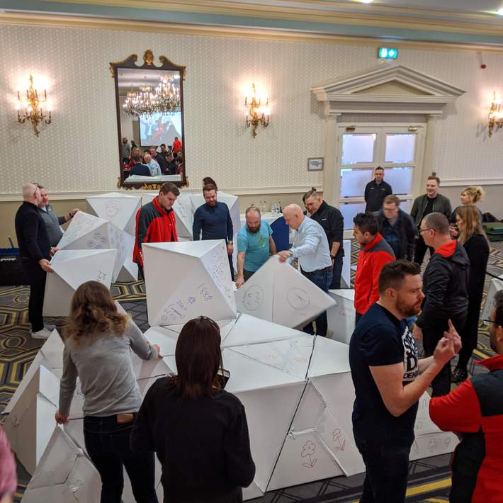 people building pyramid from cardboard blocks